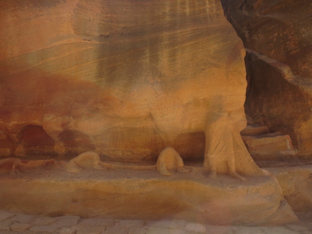 Rock carving in the siq - you can see the lower leg and feet of the camel driver in bottom right; moving to the left are the two sets of padding hooves of the lead camel; the vestiges of the camel's hump appear on the wall above; the height was about four metres 